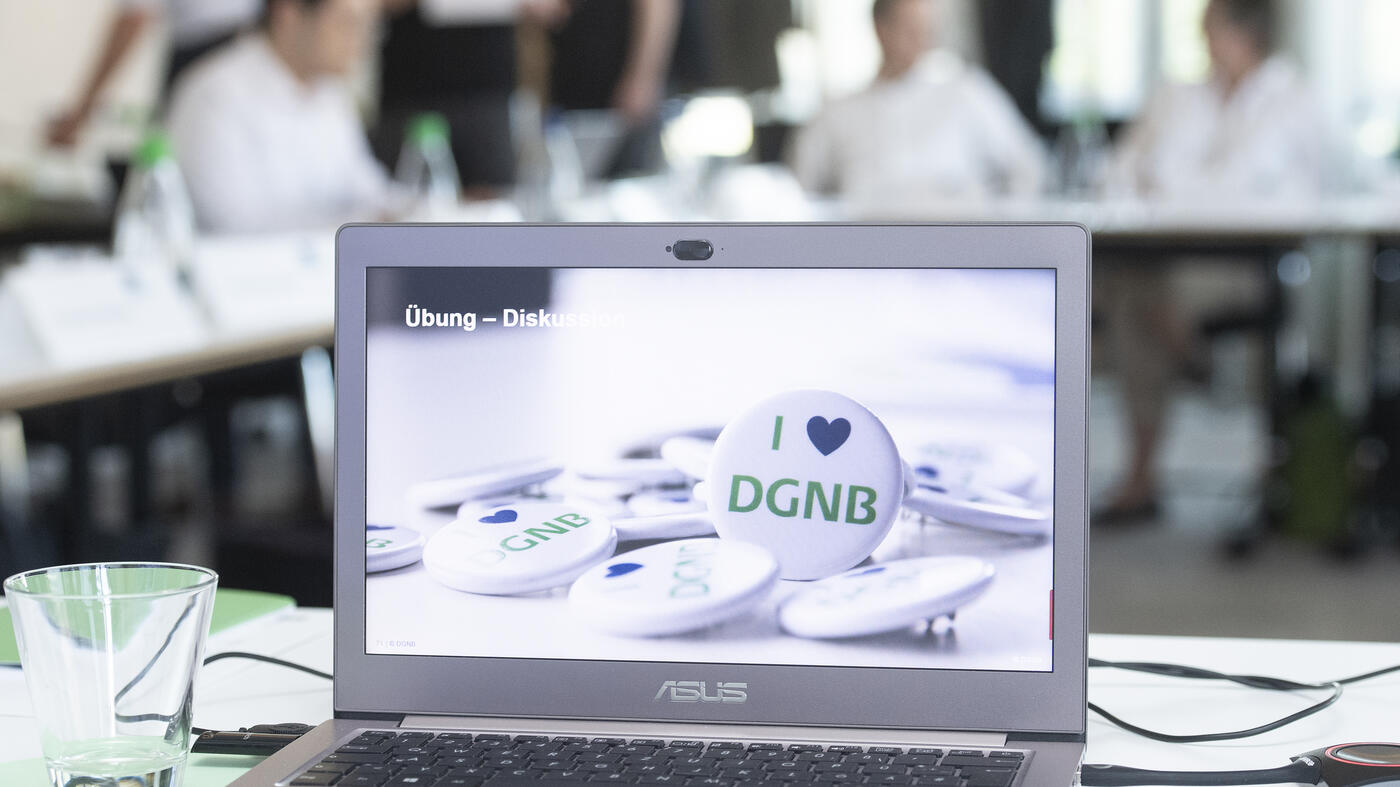 Aufgeklappter Laptop mit I love DGNB Buttons als Hintergrund