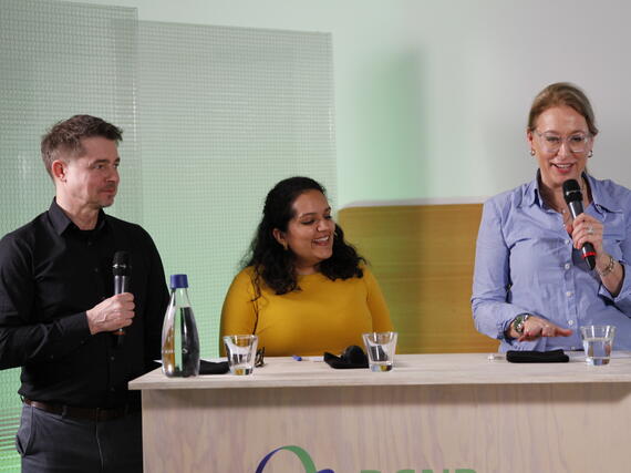 Auf dem Bild sind Matthias Schäpers, Seema Issar und Dr. Christine Lemaitre (alle drei von der DGNB) hinter einem Podium zu sehen. Christine Lemaitre hält ein Mikrofon in der Hand.