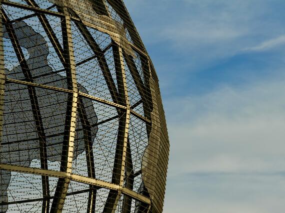 Drahtkonstruktion von Globus vor blauem, leicht bewölktem Himmel