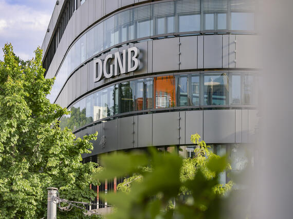 Aufnahme der DGNB Geschäftsstelle von außen mit Schriftzu an der Fassade und Baum in der unteren linken Bildecke